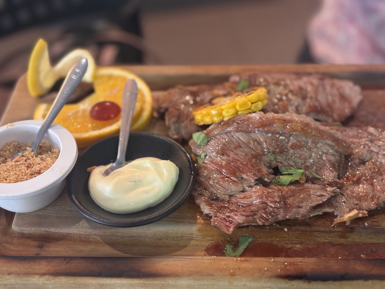 Tábua de carne grelhada com milho, laranja e farinha de mandioca.